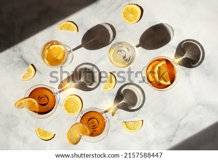 Summer cocktails in the sunlight. Fresh juicy beverages in glasses with shadows making trendy pattern. Delicious lemonade, cold tea, soda and water on gray marble background