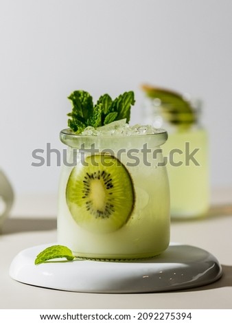 Summer cold drink and beverage recipes. Kiwi Lime Mojito cocktail or non-alcoholic cocktail with lemon, mint and fruit on white background.