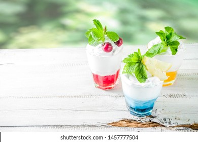 Summer Cold Drinks. Colorful Italian Cream Soda Cocktails Over White Wooden Background Copy Space