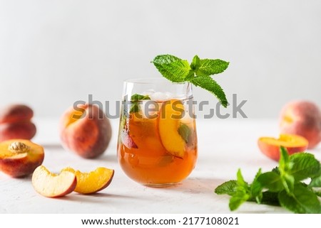 Summer cold peach fizz cocktail or iced tea with mint. Two glasses with peach lemonade on white background. Summer refreshing drink recipe. Homemade fruit tea with ice. Restaurant menu. Copy space