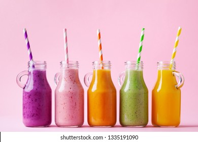 Smoothies de frutas coloridas de verão em potes em fundo rosa. Conceito de alimentos saudáveis, desintoxicantes e dietéticos. 