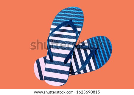 Summer colorful striped print flip flops isolated on orange background. Top view
