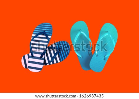 Summer colorful striped print flip flops isolated on red background. Top view