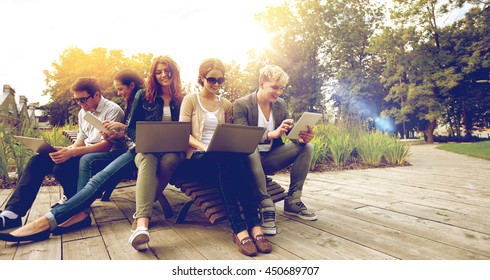 Summer, Communication, Technology , Education And Teenage Concept - Group Of Students Or Teenagers With Laptop And Tablet Pc Computers At Park Or Campus