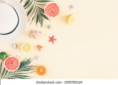 Summer composition. Fruits, hat, tropical palm leaves, seashells on pastel yellow background. Summer concept. Flat lay, top view, copy space