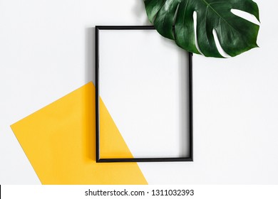 Composición veraniega. Hojas tropicales de palma, papel amarillo en blanco, marco fotográfico de fondo gris pastel. Concepto de verano. Diseño plano, vista superior, espacio de copia