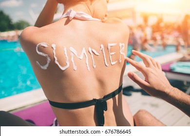 Summer Concept. Man Writing The Word Summer On A Woman's Back. Man Applying Sunscreen On The Skin Of A Girl