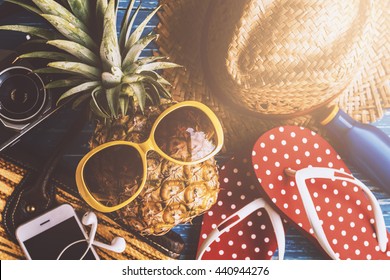 Summer concept with pineapple and essentials of traveler, Vacation background with beach items on wood table - Powered by Shutterstock