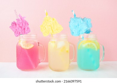 Summer cotton candy lemonade drinks. Three colors in mason jar glasses against a pastel pink background.