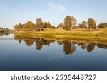 Summer country landscape at sunset. Narrow suspension bridge over the Olonka River in the village of Verkhovye, Olonetsky district, Karelia