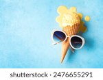 Summer creative concept with melting ice cream cone and sunglasses on blue background, copy space. Trendy beach relax and summer vacation theme.