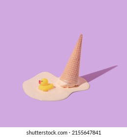 Diseño creativo de verano con cono de helado derretido boca abajo y juguete de pato de goma sobre fondo púrpura pastel. El concepto de helados estéticos de moda retro de los años 80 o 90. Mínima idea de verano.