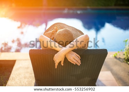 Summer day lifestyle woman relax and chill near luxury swimming pool sunbath at the beach resort outdoors the hotel.  Vacations and Summer Concept