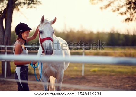 Summer day on the farm. Young girl caress horse