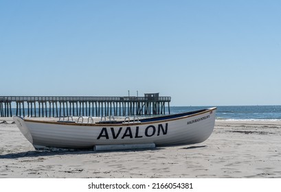 Summer Days In Avalon, New Jersey. Avalon Beach Patrol Boat On Shore With Fishing Pier In The Background.