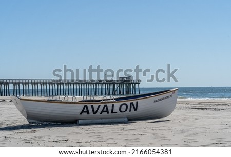 Summer days in Avalon, New Jersey. Avalon beach patrol boat on shore with fishing pier in the background.