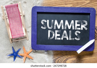  Summer Deals Text On Blackboard. Summer Deals Text With Lounge And Starfishes, Blackboard And Sand.