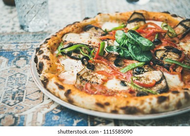 Summer dinner or lunch. Freshly baked Italian vegetarian pizza with vegetables and fresh basil over oriental tile background, close-up - Powered by Shutterstock