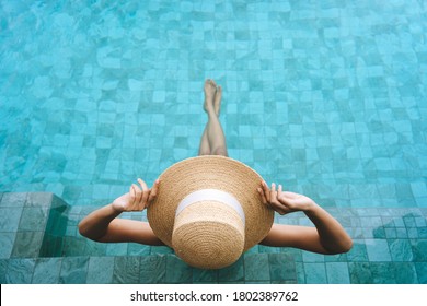El concepto de viajes domésticos de verano en Tailandia es de vacaciones. Las vistas de la parte trasera y superior de una mujer asiática se relajan en el complejo de spa de la piscina. Ella sentada junto a la piscina con sombrero de paja y bikini.