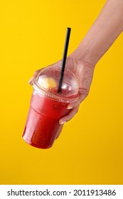 Summer Drink Fresh Lemonade With Strawberry In The Plastic Cup On Yellow Background. Female Hand Holding A Glass. Mockup For Your Advertisement.