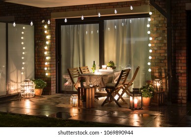 Summer evenig terrace with candles, wine and lights - Shutterstock ID 1069890944