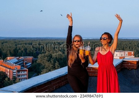 Summer event on the roof. Happy women drinking cold juice at a rooftop in sunset. Females enjoying summer in the evening looking to sunset. Love, Romantic, Friends, Party. Hen-party
