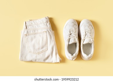 Summer fashio set with white sneakers and jeans pants, top view, flat lay on yellow backgrpund