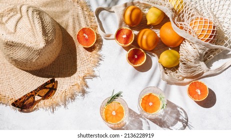 Summer fashion flat lay banner on white background. Holiday party, vacation, travel, tropical concept. Straw hat, sunglasses, refreshing drinks and citrus fruits. Palm shadow and sunlight. Top view
