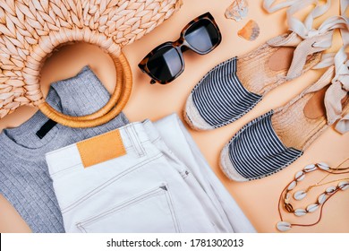 Summer Fashion Flatlay With White Denim Jeans, Silver Top, Summer Straw Bag, Striped Espadrilles Sandals, Sea Shell Necklace And Tortoiseshell Sunglasses Isolated On Beige Background.