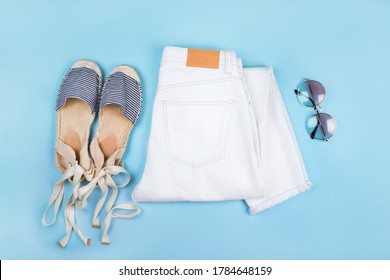 Summer Fashion Flatlay With White Denim Jeans, Striped Espadrilles Sandals And Tortoiseshell Sunglasses Isolated On Blue Background.