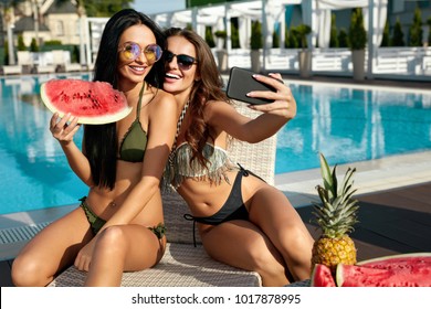 Summer Fashion. Girls Having Fun Taking Photos Near Pool. Sexy Women In Trendy Sunglasses And Fashionable Bikini Swimwear Making Selfies And Enjoying Luxury Vacation At Resort Hotel. High Resolution.