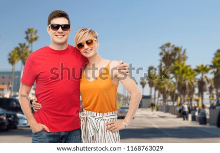 summer fashion, style and people concept - smiling couple in sunglasses hugging