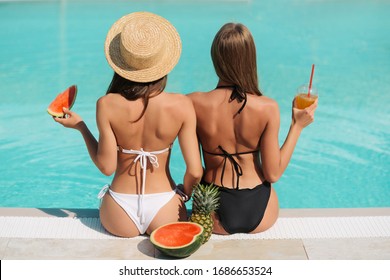Summer Fashion. Two girls with sexy bodies in swimsuits near pool. Back view of beautiful girls with fit butt in fashionable swimwear relaxing near pool at luxury resort. High Quality Image