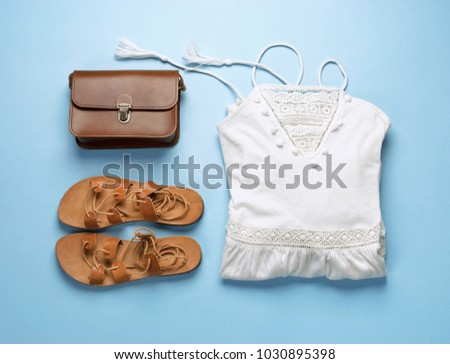 Summer festive background, beach female accessories white sundress, leather sandals and bag on a blue background. Vacation and travel items. Top view Blue Background Flat Lay