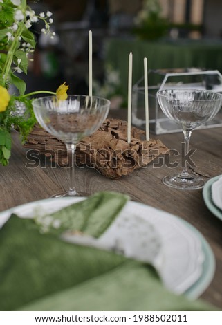 Summer festive table setting. Wedding decoration of the banquet hall. Natural materials. Wooden table, velvet tablecloth. Green color. Soft light. Natural flowers. Plates and glasses. Stylish party