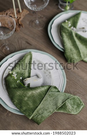 Summer festive table setting. Wedding decoration of the banquet hall. Natural materials. Wooden table, velvet tablecloth. Green color. Soft light. Natural flowers. Plates and glasses. Stylish party