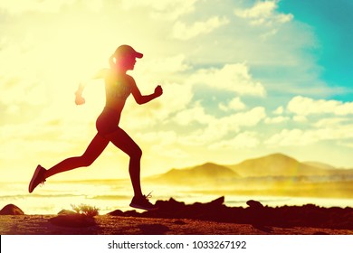 Summer Fitness Healthy Active Woman Running On Beach Against Sun Flare At Sunset. Runner Athlete Sport Girl Jogging On Trail Run Race On Nature Landscape. Fit Active Lifestyle.