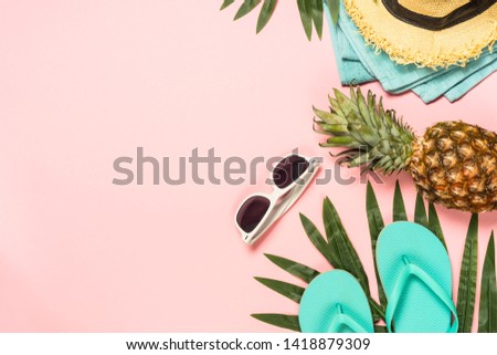 Summer flat lay background. Beach accessories with palm leaves, flip flops, pineapple, sunglasses, hat and starfish on pink background. Top view with copy space.