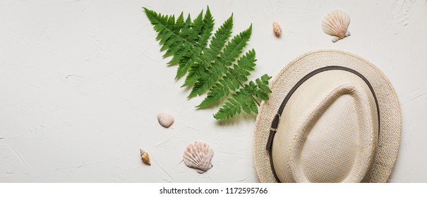 Summer Flat Lay With A Hat And A Green Fern, A Red Sea Star, Seashells And Glasses On White Concrete Background.