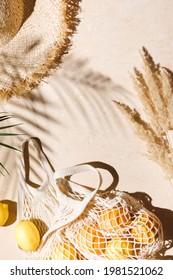 Summer Flat Lay On Beige Background. Straw Hat And Lemon Fruits In Eco Friendly Mesh Shopping Bag. Trendy Palm Shadow And Sunlight, Sun. Minimal Summer Travel Fashion Concept. Top View