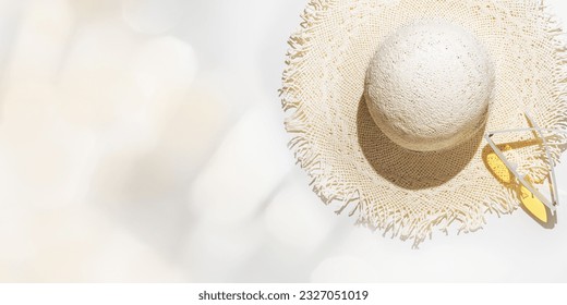 Summer flat lay straw sun hat and yellow sunglasses at sunlight on  light grey background with blurred bokeh glare as copy space. Aesthetic Life style summer holidays photo, beige pastel color banner