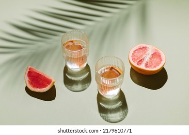 Summer flat lay with two glasses of refreshment drinks and grapefruit slices on green background with palm leaf shadow sun and sunlight. Vacation, holiday, mocktail, creative minimal concept - Powered by Shutterstock