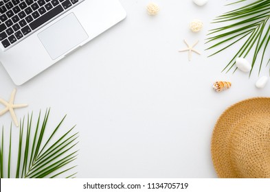 Summer flat lay. Work and travel concept. Rest, sea, sun, beach and work. Frame from laptop, green leaves, seashells and straw hat.