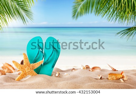 Summer flipflop on sandy beach, blur sea on background. Summer exotic relaxation concept