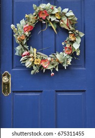 A Summer Floral Wreath Hanging On Blue Door.