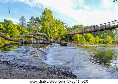 The summer flow of a stream underneath a walking bridge at a public park in Pennsylvania.