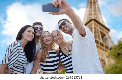 Summer, France, Tourism, Technology And People Concept - Group Of Smiling Friends Taking Selfie With Smartphone Over Eiffel Tower In Paris Background