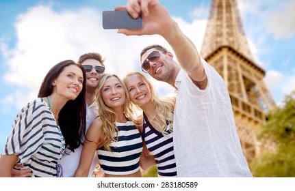 Summer, France, Tourism, Technology And People Concept - Group Of Smiling Friends Taking Selfie With Smartphone Over Eiffel Tower In Paris Background