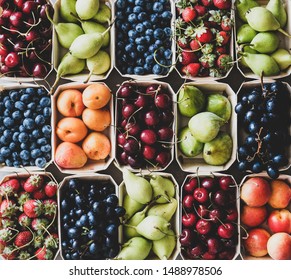 Summer fruit and berry assortment. Flat-lay of strawberries, cherries, grapes, blueberries, pears, apricots, figs in eco-friendly boxes over grey background, top view, close-up. Local farmers produce