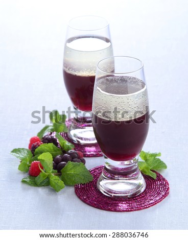 Summer fruit cocktail layered of red raspberry blackberry currant with mint in a glass on a blue tablecloth